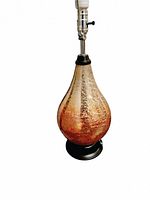 Close-up of the textured amber glass teardrop-shaped lamp base with dark metal base, without shade, showing the bulb socket.