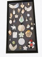 Top-down angle showing all 31 shell and pearl pendants arranged on black tray, showcasing the variety in shapes, sizes, and colors.