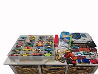 Photo of over 80 assorted vintage toy cars in storage cases and loose on a table, showing various types and colors.