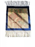 Front side of a small hand-knotted rug featuring a peacock woven in beige, green, and blue colors with a blue border and fringes.