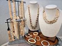 Wide view of lot showing necklaces on busts and bracelets on tray and stand