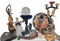 Various decorative candle holders, figurines and a clear crystal ball on a wood pedestal