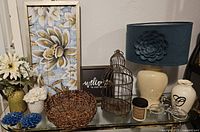 Full lot on glass cabinet showing all items; lamp, framed art, bird cage, candles, vases, basket, flowers, and sign