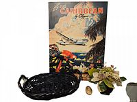 Photo showing all four items together: vintage Caribbean travel poster, navy blue basket, floral arrangement, and egg-shaped souvenir stone