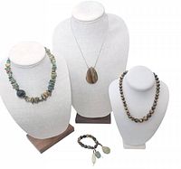 Full lot showing three necklaces on bust displays and one bracelet laid out in front