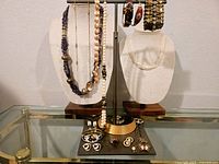 Photo of entire vintage jewelry lot displayed on stands and trays showing necklaces, bracelets, earrings, and ring.