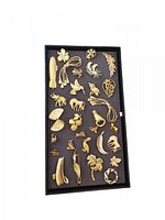 Tray holding 30 various gold-toned vintage pins and brooches neatly arranged.