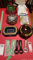 Lot overview showing multiple branded ashtrays and bottle openers on red table