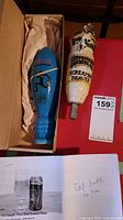 Photo showing two beer tap handles side by side in a box: blue Prison Break handle and Copperhead Screamin Beaver handle.