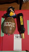 Photo showing Rogue barrel beer tap handle with a man holding a mug and Goose Island 312 Urban Wheat Ale black telephone handset tap handle.