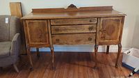 Full view of the wood buffet showing three central drawers and side cabinets with decorative inlay doors and cabriole legs.