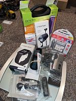 Photo showing all items together - Andis clippers, Fitbit Versa and Flyer, Bosch GLM40, battery kit, Panasonic recorder, scale, and accessories on carpeted floor