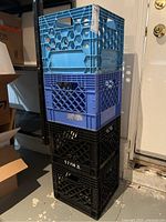 Stack of six milk crates in blue, light blue, and black, showing overall condition and color variety.