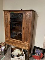 Full view of the vintage solid wood china cabinet showing glass door with carved arch trimmed cleft design, wood inlay on front panels, and tapered legs.