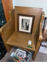 Wooden pew with framed religious print resting on the pew seat, showing the wood grain and cross side detail.