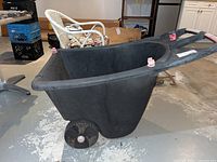 Side angle of black yard cart showing one wheel and handle with pink grips.