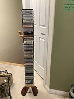 Tall, narrow metal CD storage shelf filled with stacked CDs.