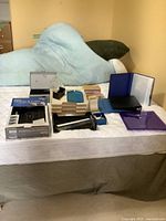 Craft supplies on bed including binders, wooden holders, stamp kit, stamping blocks, and paper trimmer.