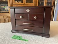 Front view of closed wooden jewelry box with drawers and lock plate.