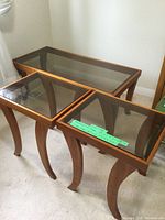 View of the coffee table and two end tables together showing the smoked glass tops and cherry wood curved legs.
