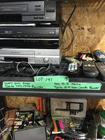 Multiple home entertainment electronics stacked on a shelving unit including Sony DVD player, Toshiba VHS/DVD recorder, Sony Hi-Fi stereo, and Toshiba Hi-Fi video cassette recorder with cables and remotes visible.