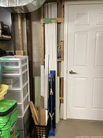 Wide shot of saw horses placed standing vertically against wall with grouped white MDF molding pieces.