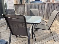 Patio table with four mesh chairs around it on a wooden deck, showing the main set.