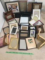 Overall assortment of 22 photo frames of various shapes, finishes and sizes, mostly empty or with placeholder inserts, one showing wedding photo