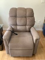 Front view of light brown upholstered power lift recline chair with remote hand control on armrest.