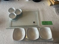 Photo showing all items in the lot: glass tray, three-section bowl, and three small bowls on table with textured white tablecloth.