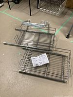 Two-tier sliding metal wire baskets with installation instructions laid out on the floor