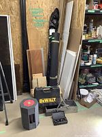 Wood trim and panels standing against wall next to rolls of vapour barrier sheeting and a DeWalt tool box on floor with tools nearby.