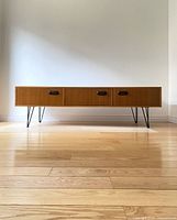 Front view of teak veneer TV stand showing three compartments and hairpin legs