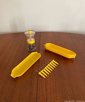Photo showing four yellow corn-shaped dishes, ten corn holders, and one salt & pepper shaker placed on wooden table.