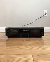 Front view of the Sony stereo cassette deck showing dual cassette compartments, digital display, and control panel with buttons and info labels.
