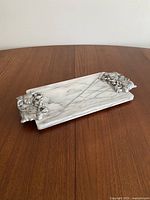 Full view of the rectangular marble tray with ornate metal handles on each end displayed on a wooden surface.