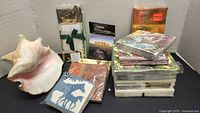 Photo of the artificial conch shell alongside various packages of paper napkins stacked in piles.