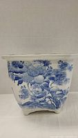 Front and side view of a square blue and white ceramic flower pot showing intricate floral design.