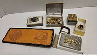 Overview of all items: wallet, buckle, lighter, boxes with tie pins/bars and rings