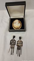 Both earrings laid out below cameo in open jewelry box