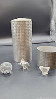 Three Swarovski crystal figurines: elephant, bird, and faceted crystal ball displayed with white and silver patterned packaging tubes.