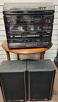 Full photo of Toshiba SL-3186 sound system stacked on a table showing turntable on top, cassette decks, radio tuner and disc player controls on front panel, and two Toshiba speakers positioned below.