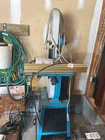 Front view of band saw on stand amid garage items