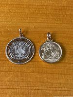 Overview of two coin pendants on wood surface