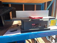 Side view of the tabletop jointer/planer on a metal shelf in a garage