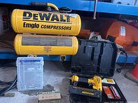 Overview of compressor, hose, brad nailer in case, box of fasteners