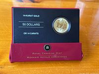 Coin displayed in original keepsake box with printed details showing “14-KARAT GOLD” and face value.