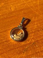 Pendant face showing gold nuggets inside clear window