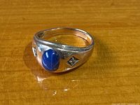 Front view showing blue cabochon center and one accent stone