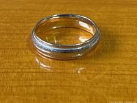 Ring laid flat on wood surface, showing white gold edges and yellow gold center